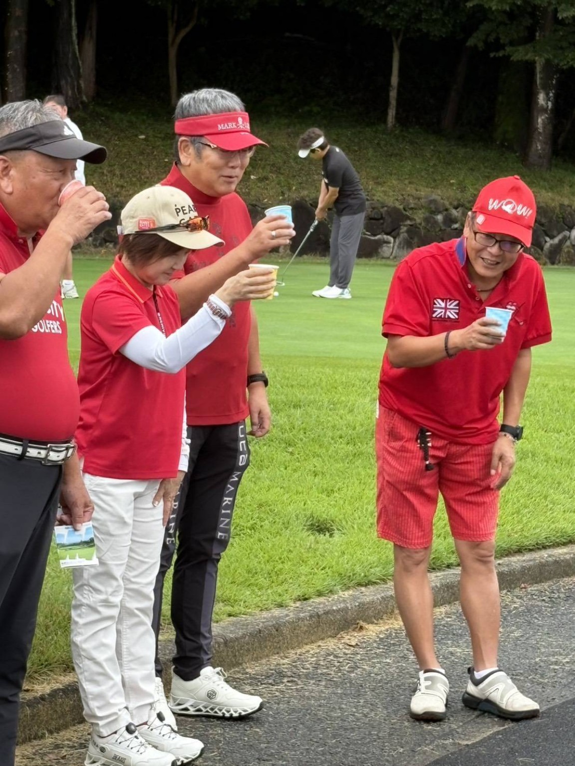 ゴルフ場でカップを持つ参加者